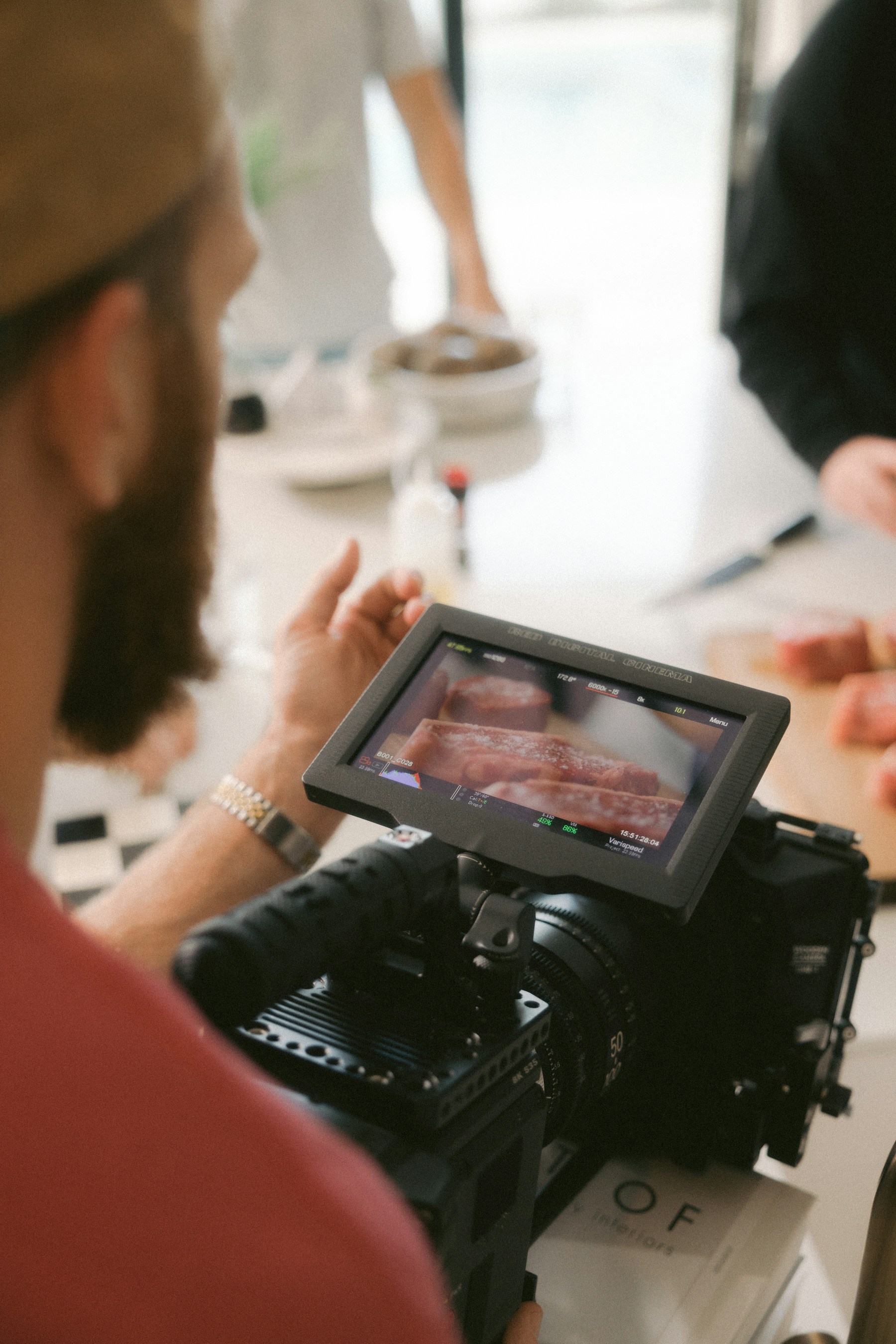 A camera operator framing a food shoot on a production monitor; illustrative stock photography