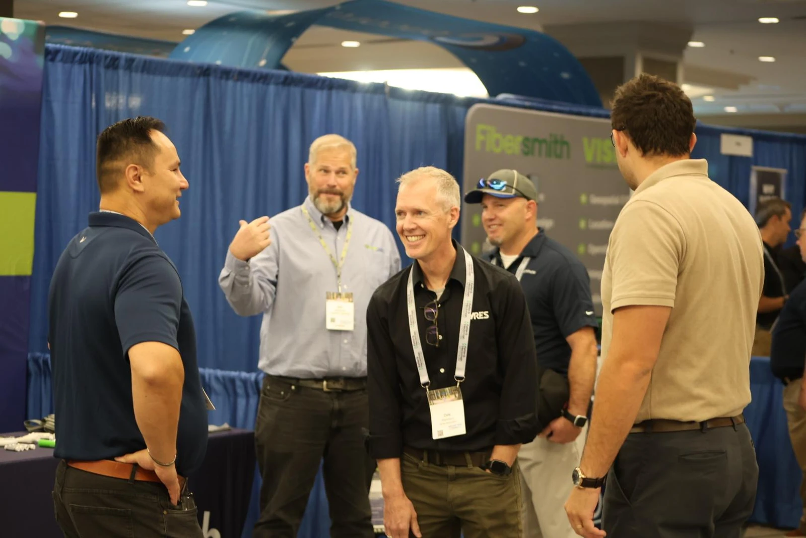 A smiling group in conversation beside exhibition booths